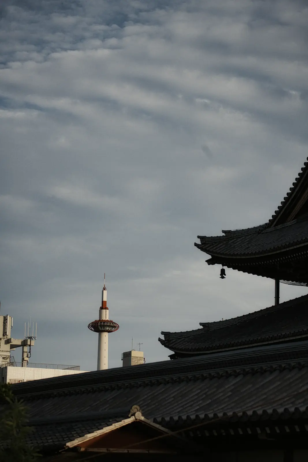 Kyoto Tower behind temple roofs under a grey sky, one of my photographs
